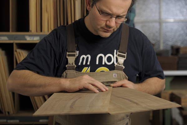 Ein Mitarbeiter prüft das Holz vor der Verarbeitung.