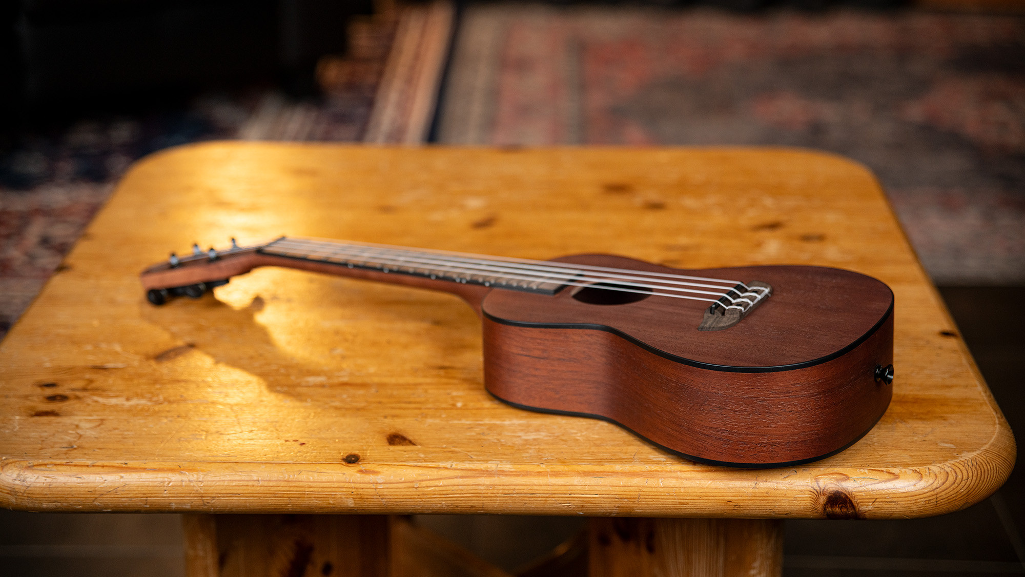 Eine braune Ukulele von Ortega liegt auf einem hellen Holztisch